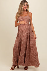 woman wearing a brown floral maxi maternity dress and gently holding her baby bump
