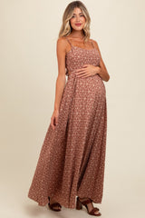 woman wearing a brown floral maxi maternity dress and holding her baby bump