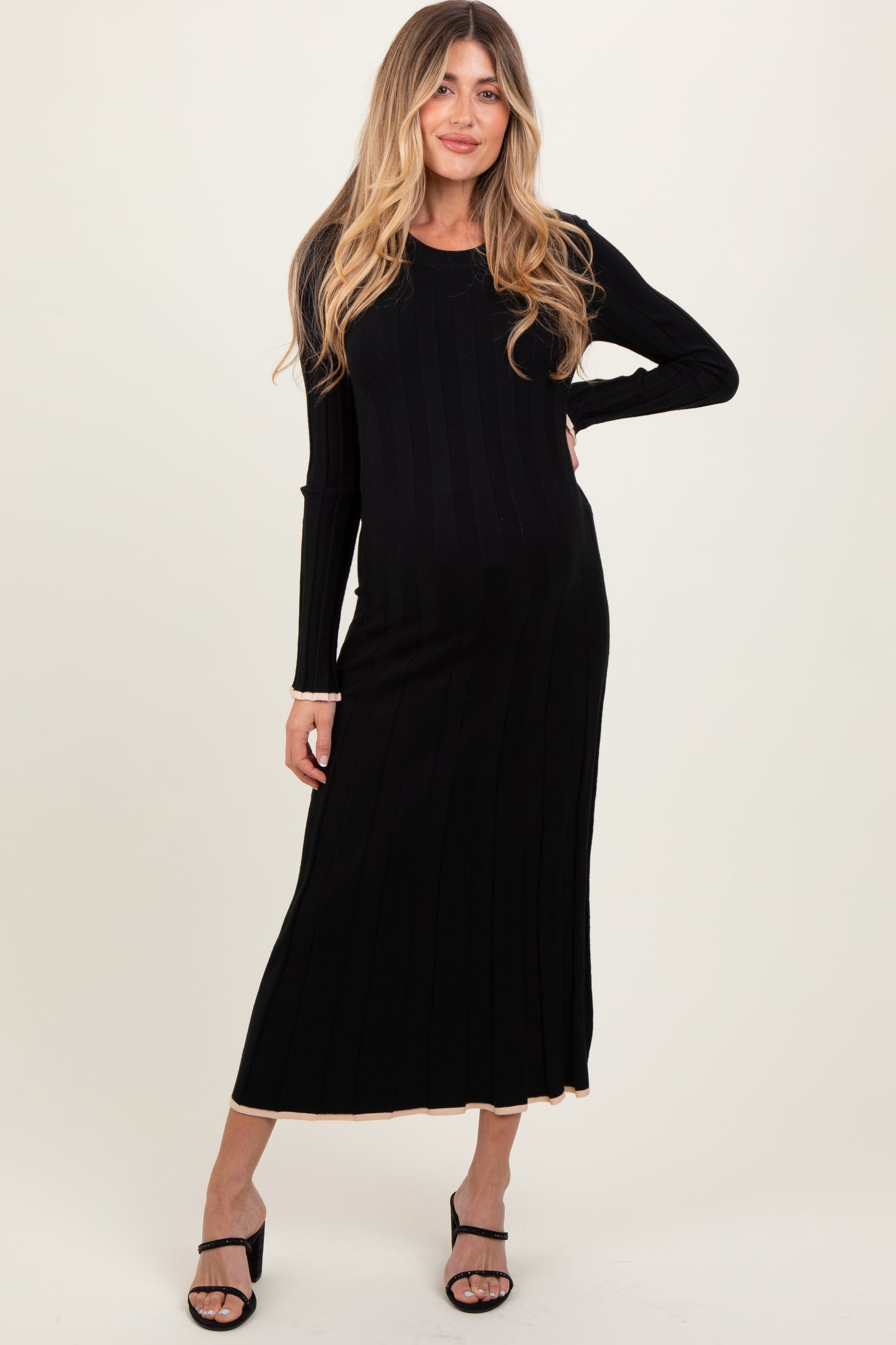 woman wearing a black ribbed maternity dress with long sleeves and a fitted silhouette, showcasing her baby bump