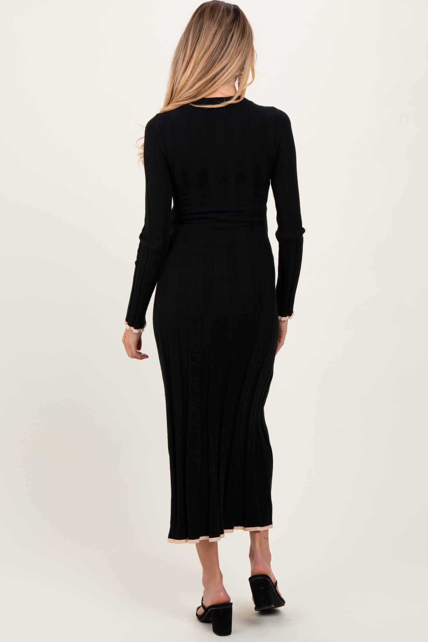 woman wearing a black ribbed maternity dress with long sleeves and a midi length, showing a baby bump from the back