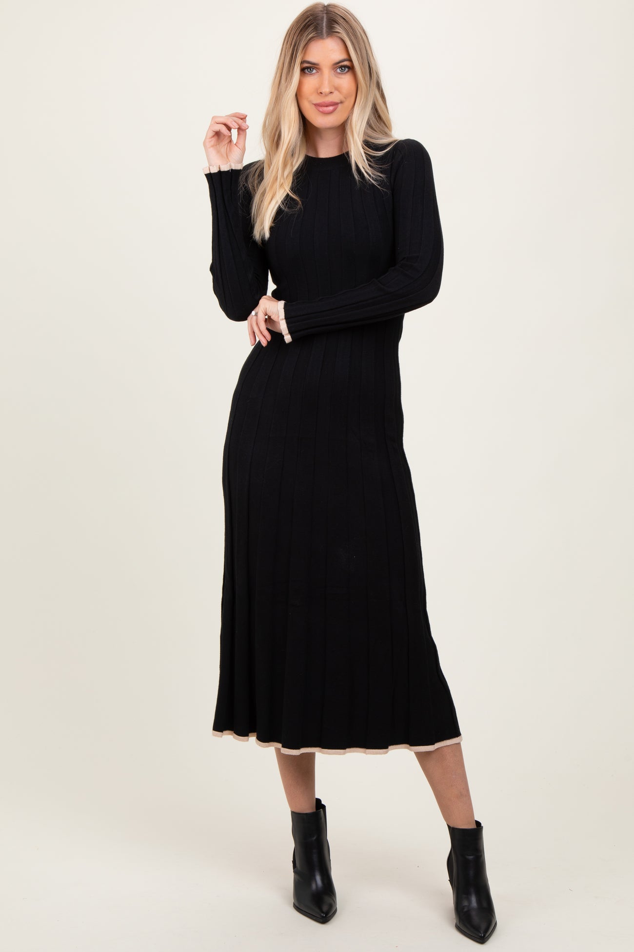 woman wearing a black ribbed long sleeve dress with a flared hem and ankle booties