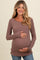 woman wearing a mauve ribbed long sleeve maternity top and holding her baby bump