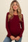 woman wearing a burgundy long sleeve maternity top with a baby bump visible