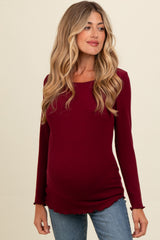 woman wearing a burgundy long sleeve maternity top with ruffled hemline and visible baby bump