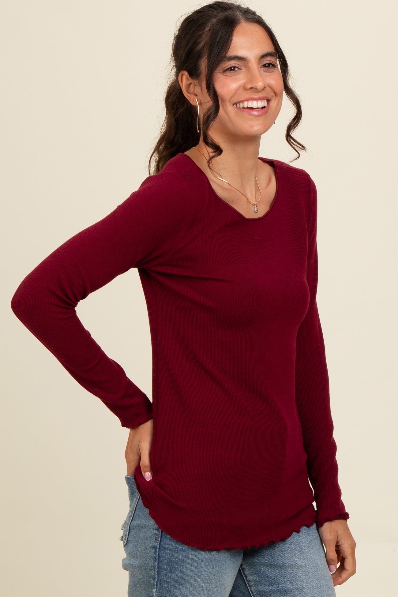 woman wearing a burgundy long sleeve ribbed top with a curved hemline and a relaxed fit