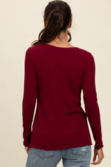 woman wearing a burgundy long sleeve ribbed top with a scoop back and raw hem details