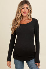 woman wearing a black long sleeve maternity top with a fitted design and side ruching, styled with blue jeans