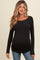 woman wearing a black long sleeve maternity top with a fitted design and side ruching, styled with blue jeans