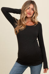 woman wearing a dark gray long sleeve maternity top and showing her baby bump