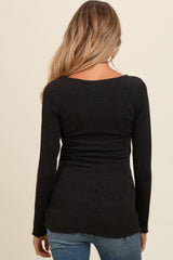 woman wearing a black long sleeve maternity top with a fitted silhouette and scoop back