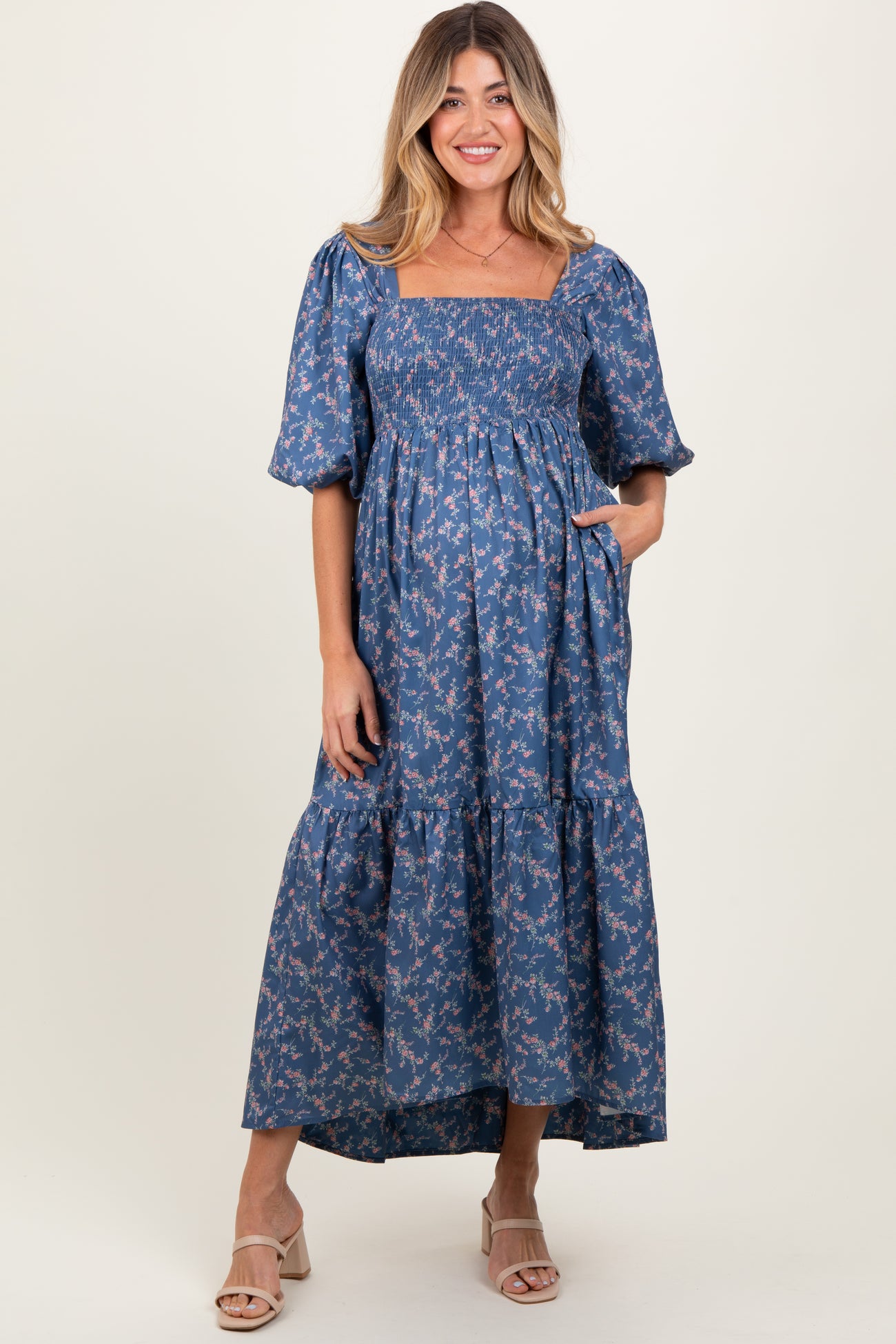 woman wearing a blue floral maternity maxi dress with puff sleeves and pockets