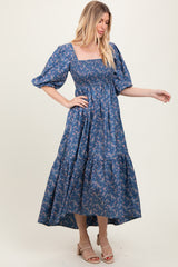 woman wearing a blue floral maxi dress with puff sleeves and a smocked bodice