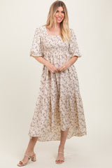 woman wearing a cream floral midi dress with square neckline and puff sleeves, standing and smiling