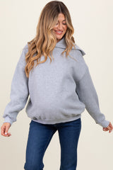 woman wearing a gray oversized maternity hoodie with a hood and a visible baby bump, paired with blue jeans