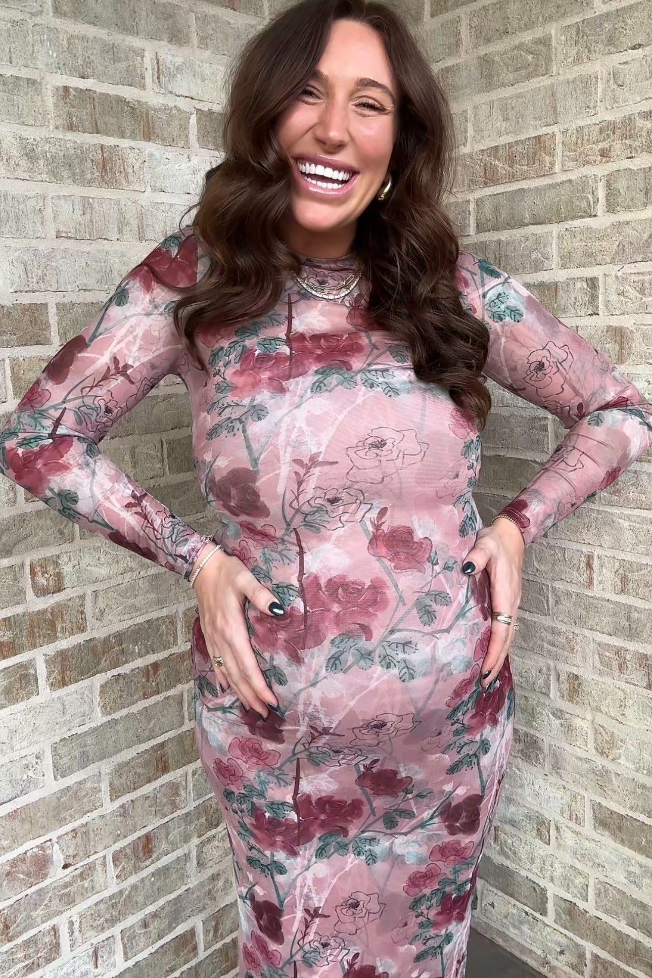 woman wearing a long sleeve pink floral maternity dress and showcasing her baby bump
