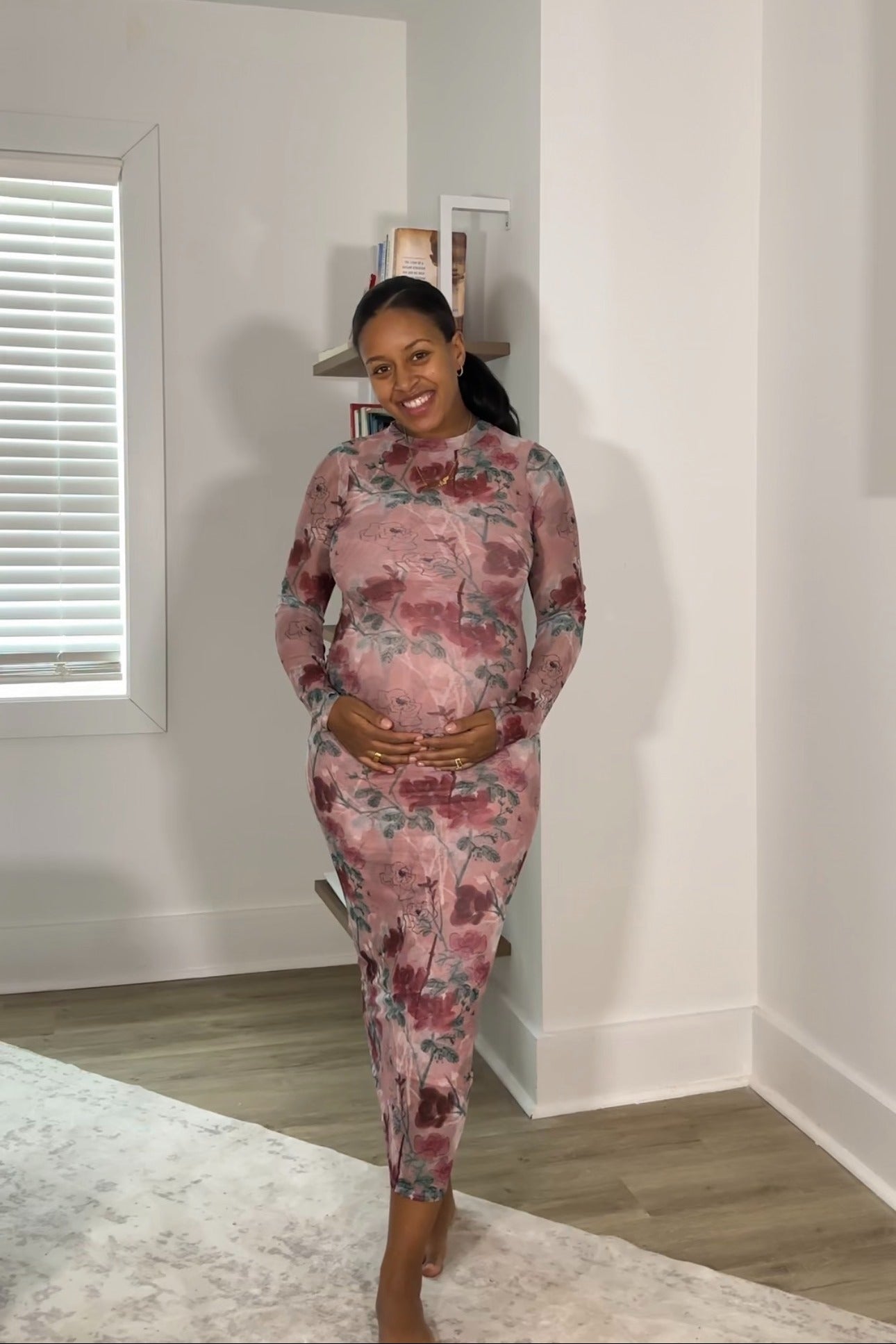 woman wearing a floral print long sleeve maternity dress and cradling her baby bump