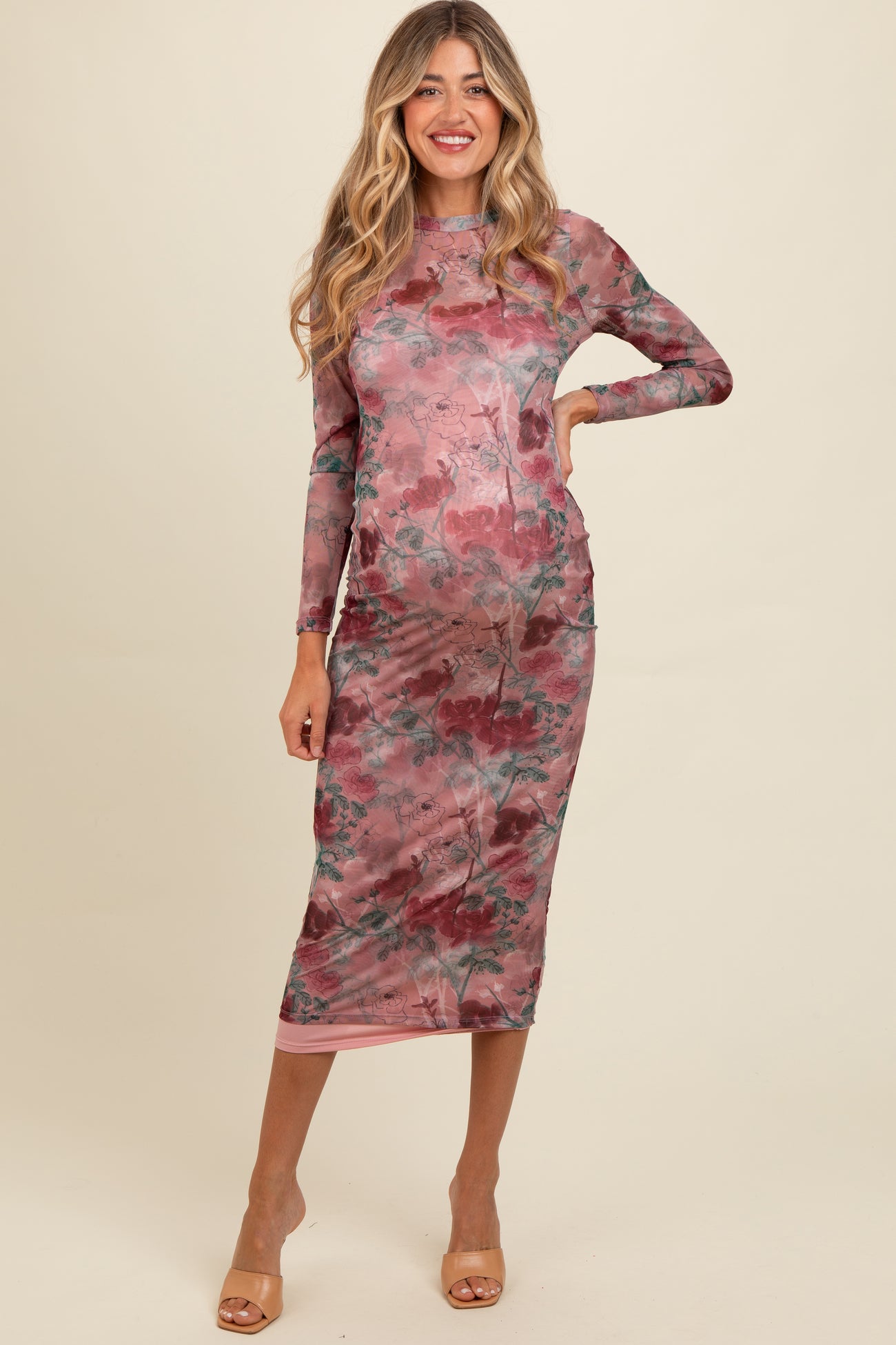 woman wearing a pink floral print long sleeve maternity dress with a fitted silhouette and a side slit