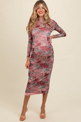 woman wearing a pink floral print long sleeve maternity dress with a fitted silhouette and a side slit