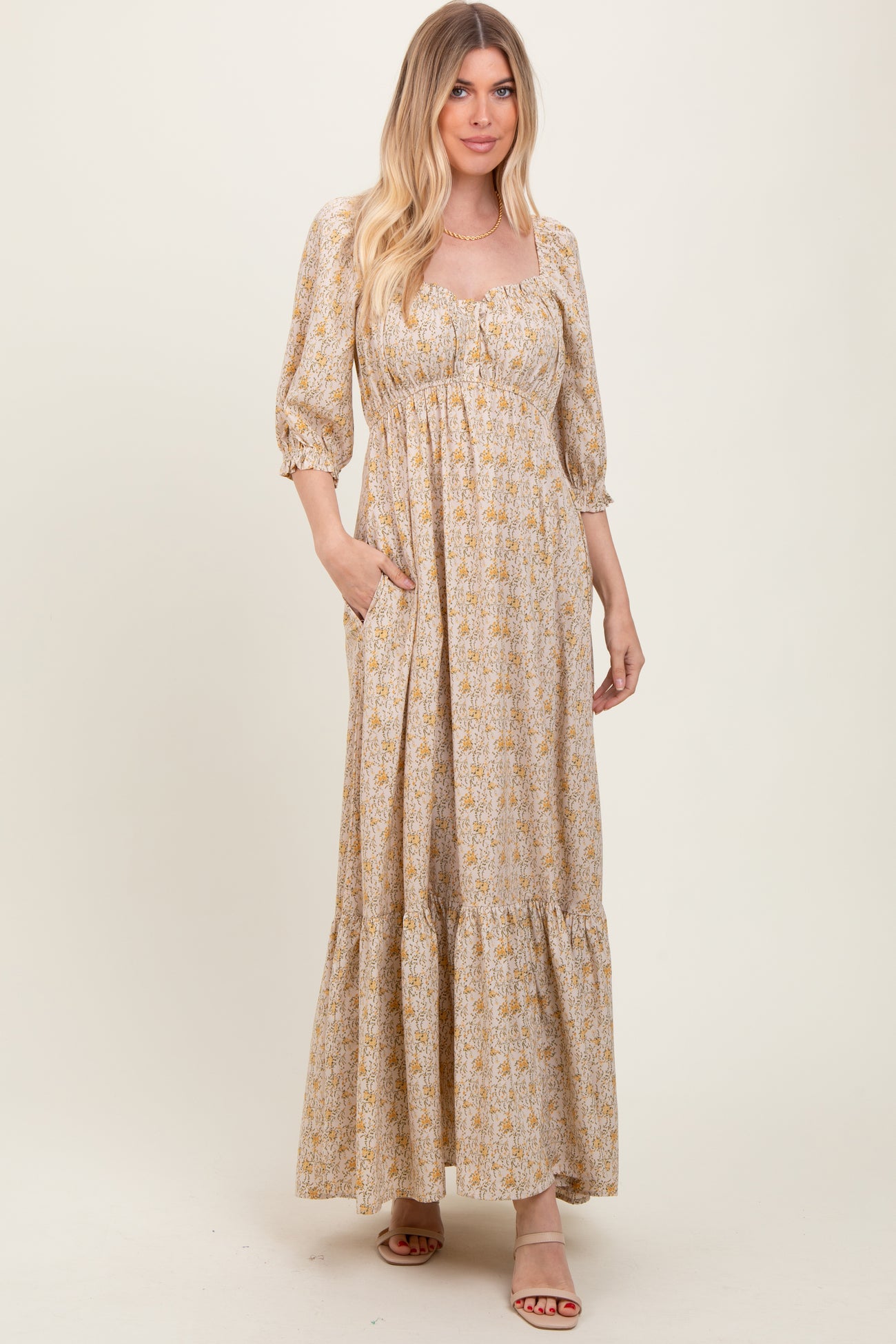 woman wearing a floral maxi dress with a square neckline and puff sleeves, features pockets and a tiered hem