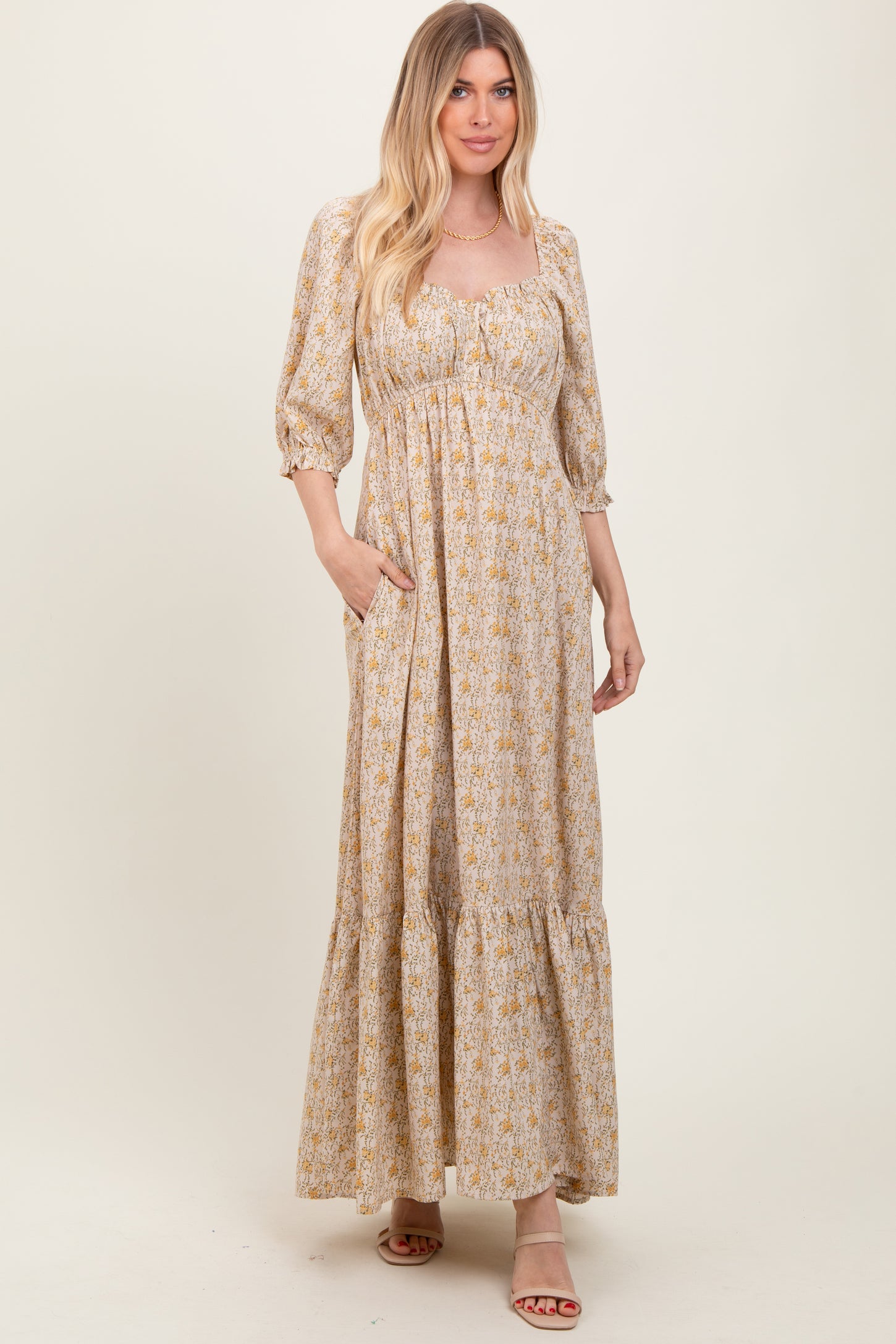 woman wearing a floral maxi dress with a square neckline and puff sleeves, features pockets and a tiered hem