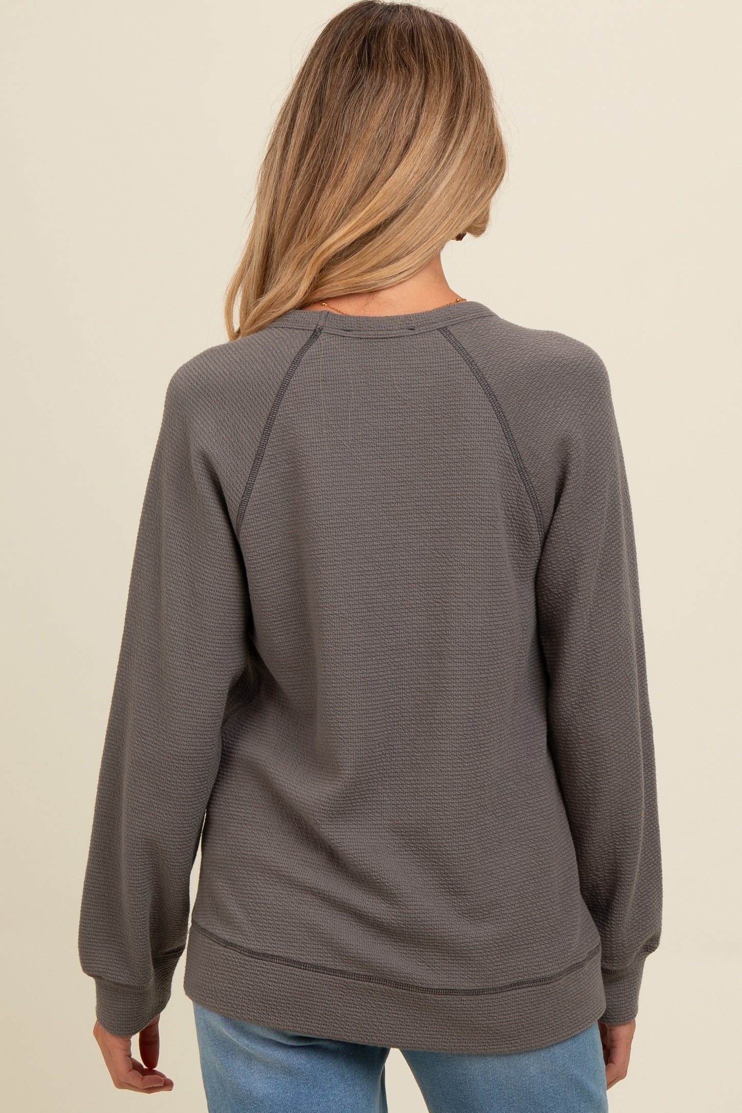 woman wearing a gray waffle knit maternity sweatshirt, view from the back