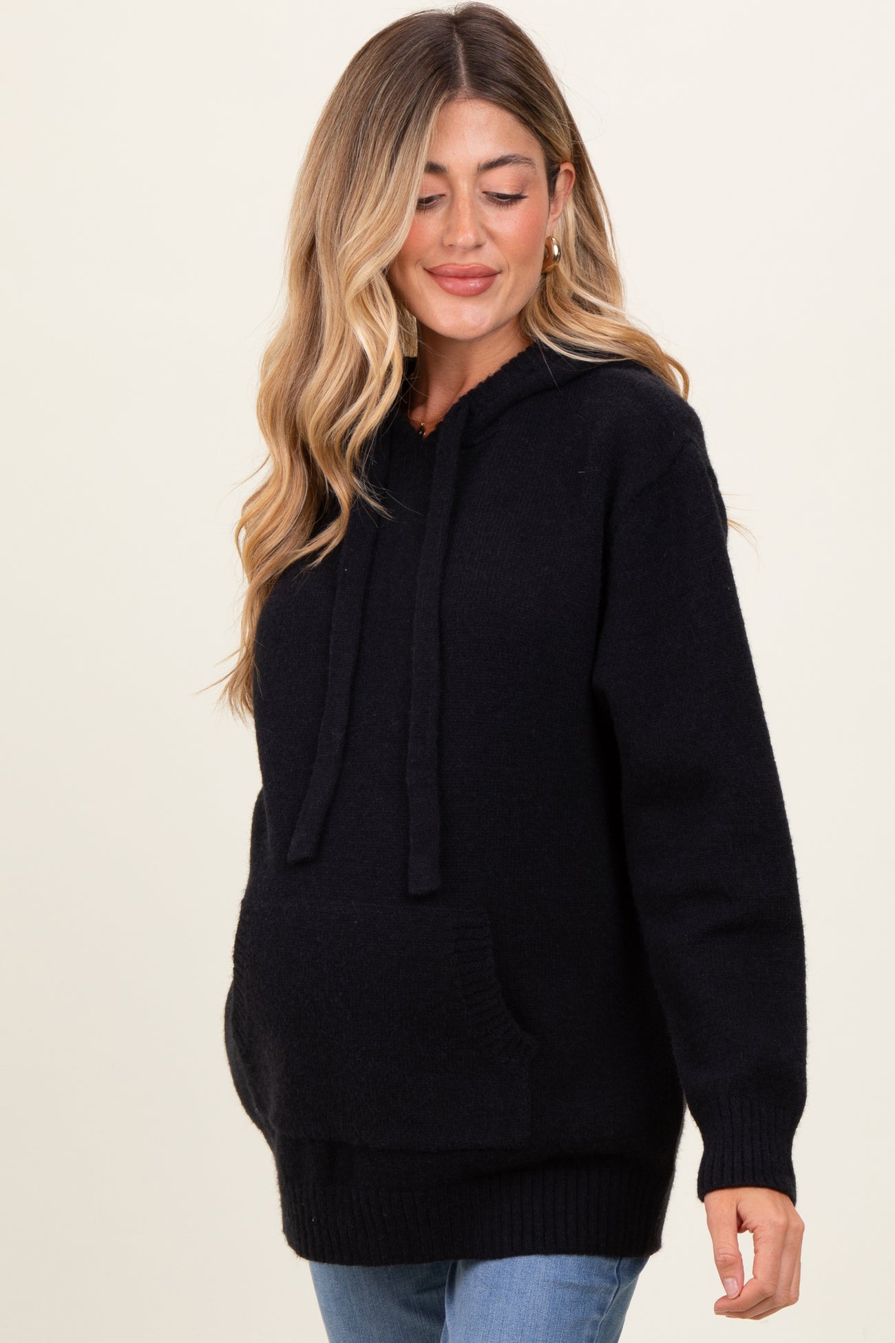 woman wearing a black maternity hoodie with a front pocket and a relaxed fit, showcasing a baby bump