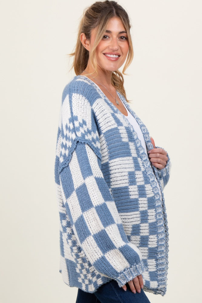 woman wearing a blue and white checkered maternity cardigan with oversized fit and long sleeves, smiling and holding her baby bump