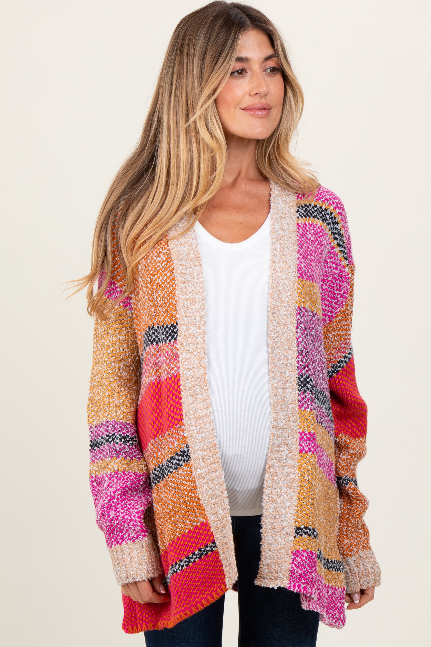 woman wearing a colorful oversized maternity cardigan over a white top and showing a visible baby bump