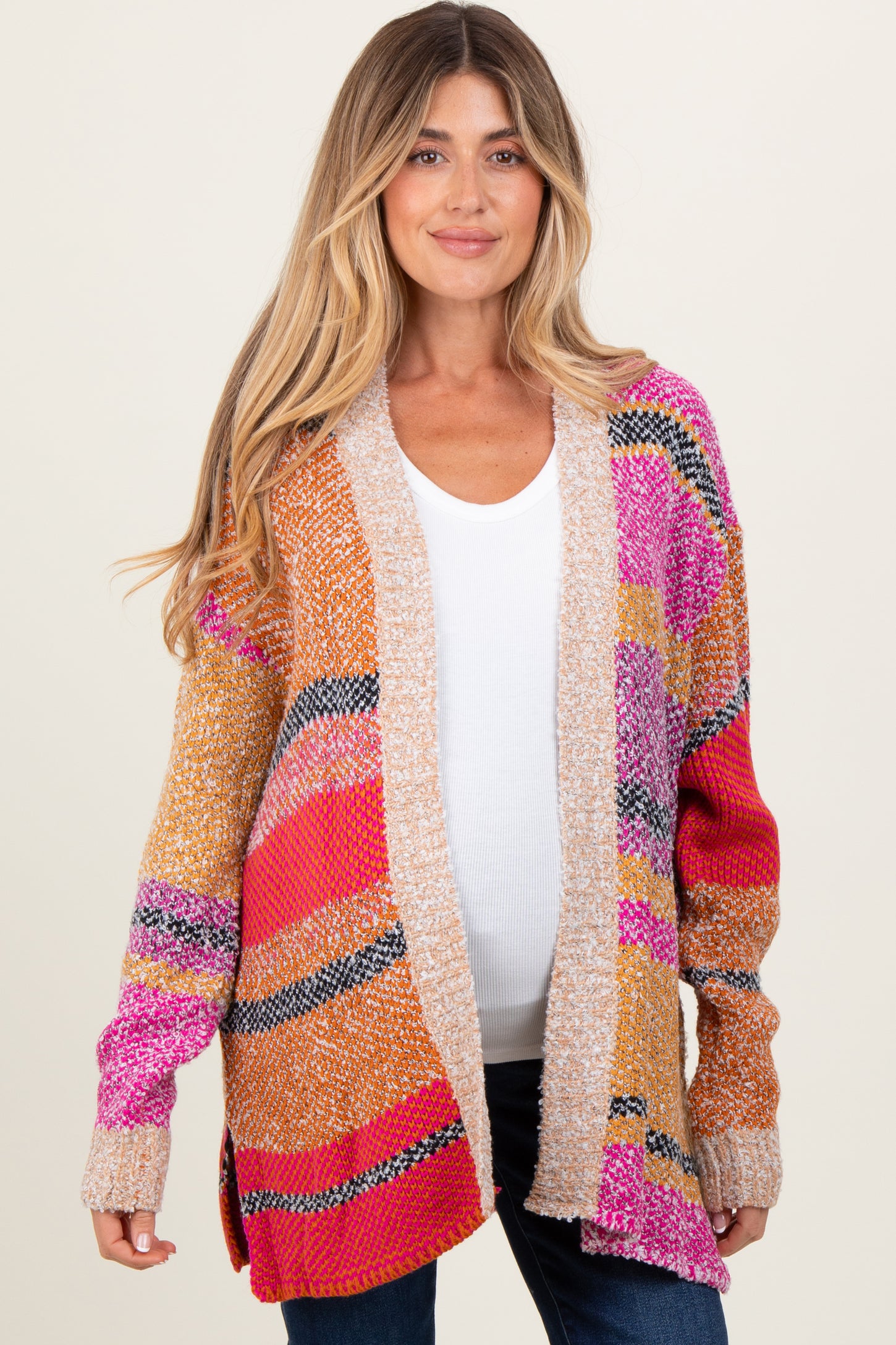 woman wearing a colorful striped maternity cardigan over a white top with a visible baby bump