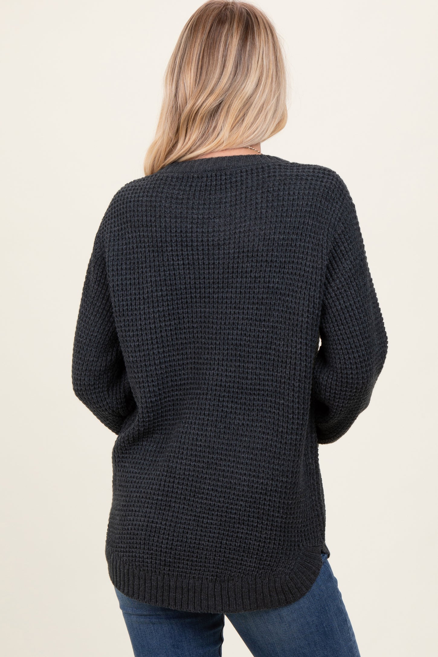woman wearing a dark gray chunky knit sweater, shown from the back with a relaxed fit and long sleeves