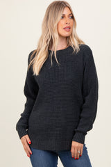 woman wearing a dark gray chunky knit sweater with long sleeves and a relaxed fit, styled with blue jeans
