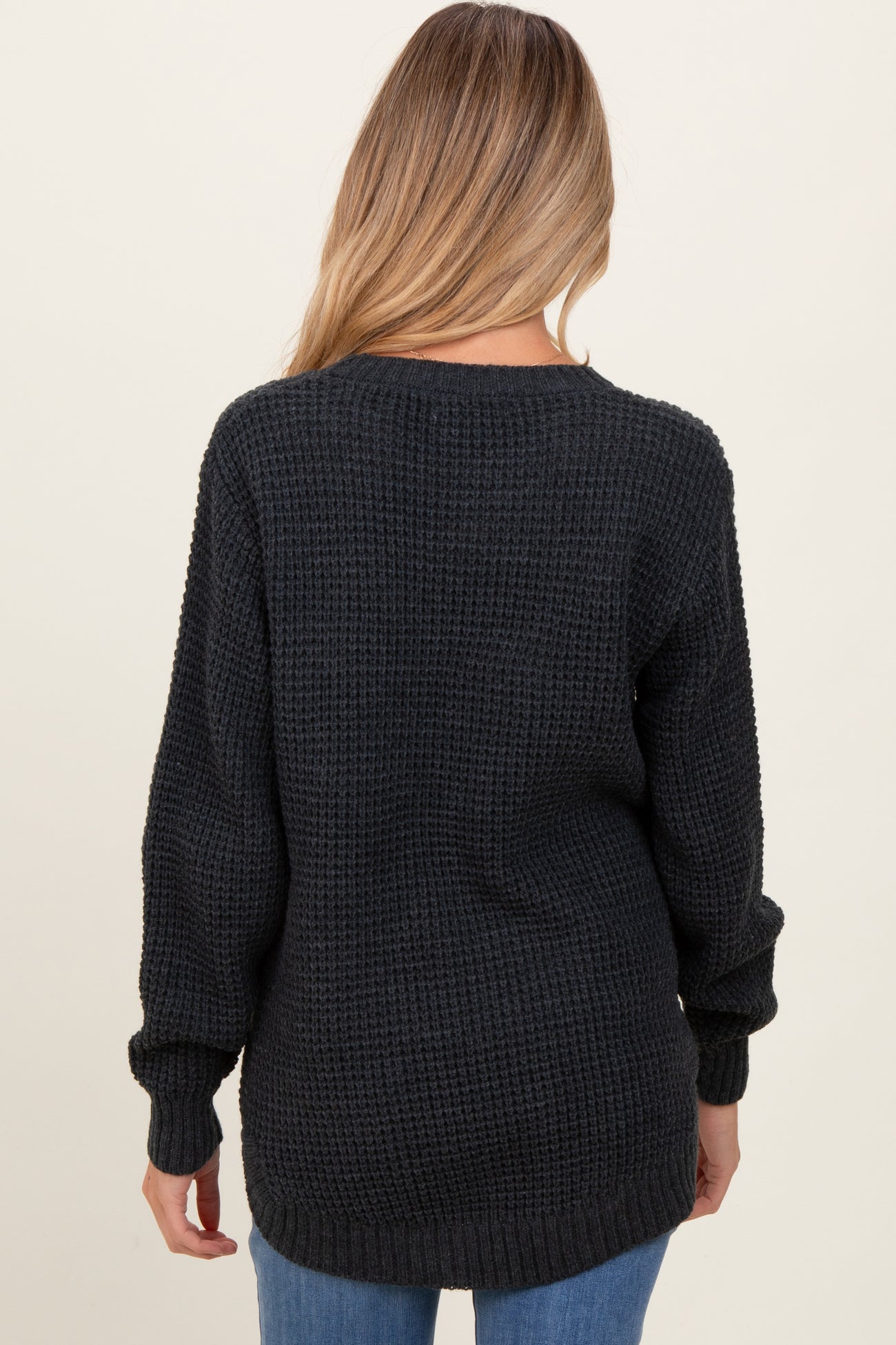 woman wearing a dark gray oversized knit maternity sweater, view of the back with long sleeves and a relaxed fit