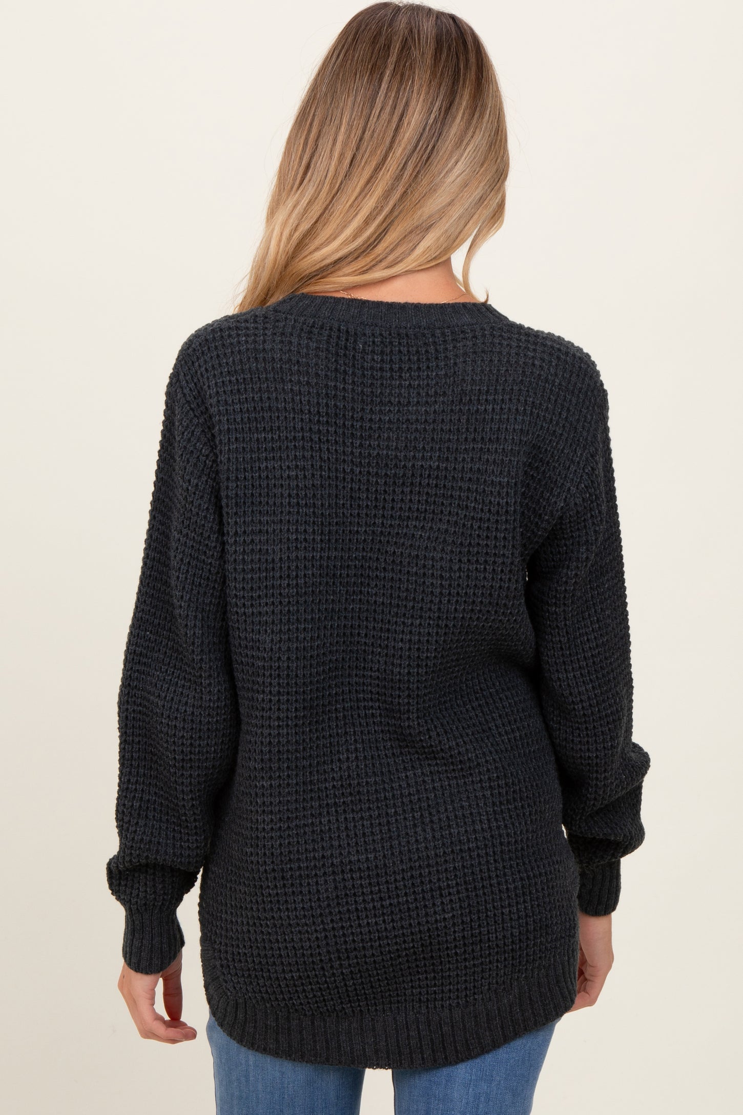 woman wearing a dark gray oversized knit maternity sweater, view of the back with long sleeves and a relaxed fit