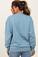 woman wearing a blue sweatshirt from the back in a maternity style with a relaxed fit and ribbed cuffs