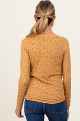 woman wearing a mustard yellow maternity top with a floral pattern and long sleeves, viewed from the back