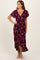 woman wearing a burgundy floral wrap dress with short sleeves and a high-low hemline