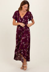 woman wearing a burgundy floral maxi dress with short flutter sleeves and a tie waist detail