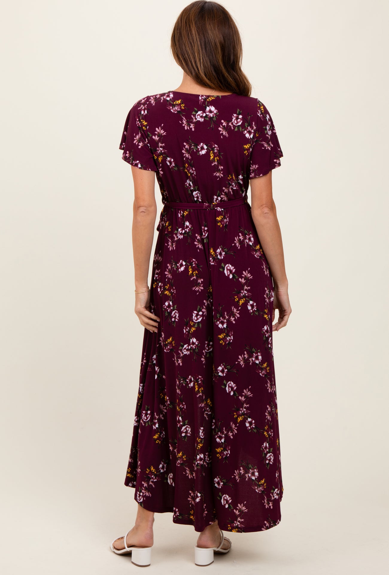 woman wearing a burgundy floral maxi dress with short sleeves and a tied waist, seen from the back