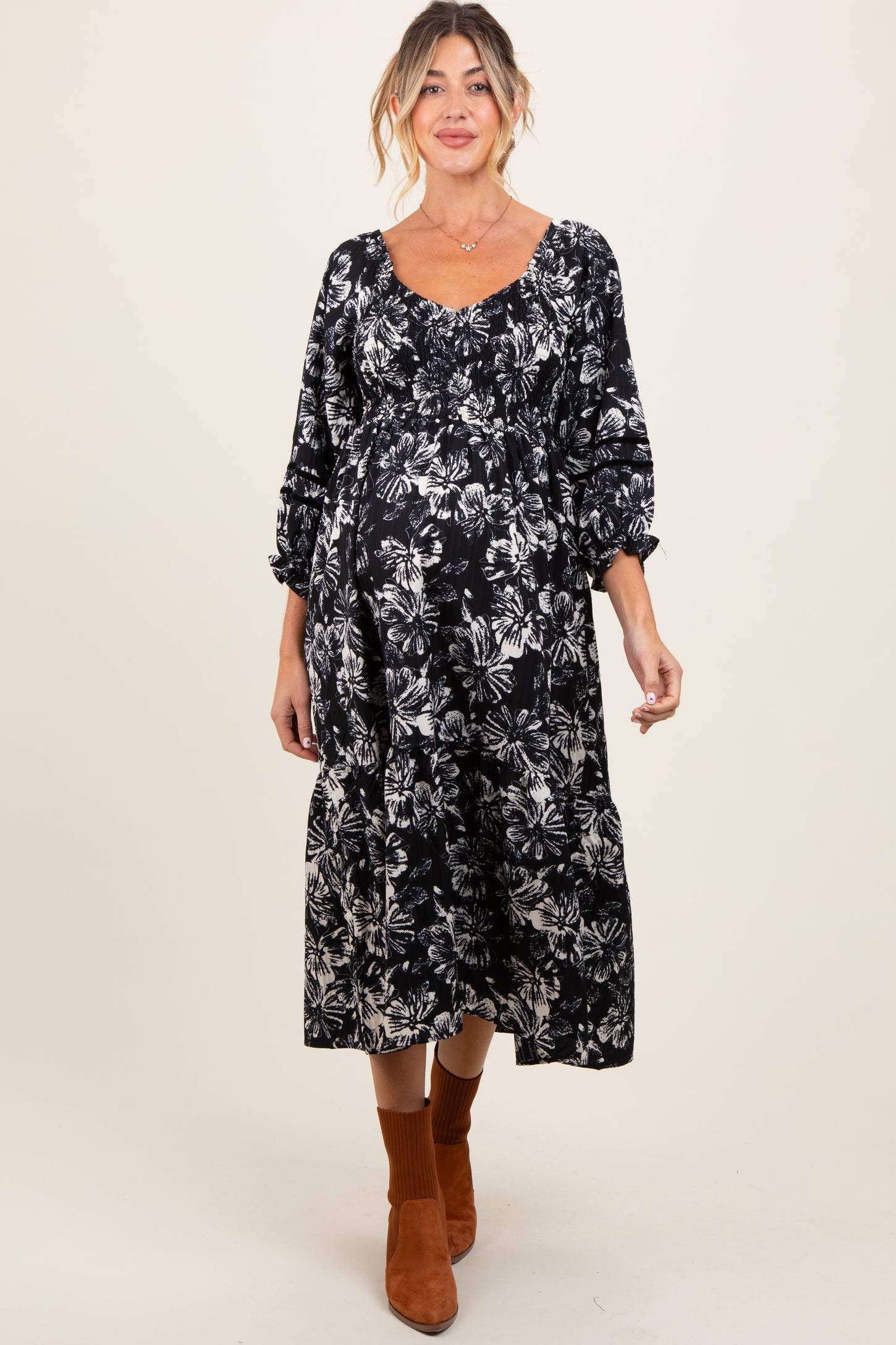 woman wearing a black floral print maternity dress with puff sleeves and a visible baby bump