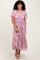 woman wearing a pink floral embroidered maxi dress with short puff sleeves and a tiered hem