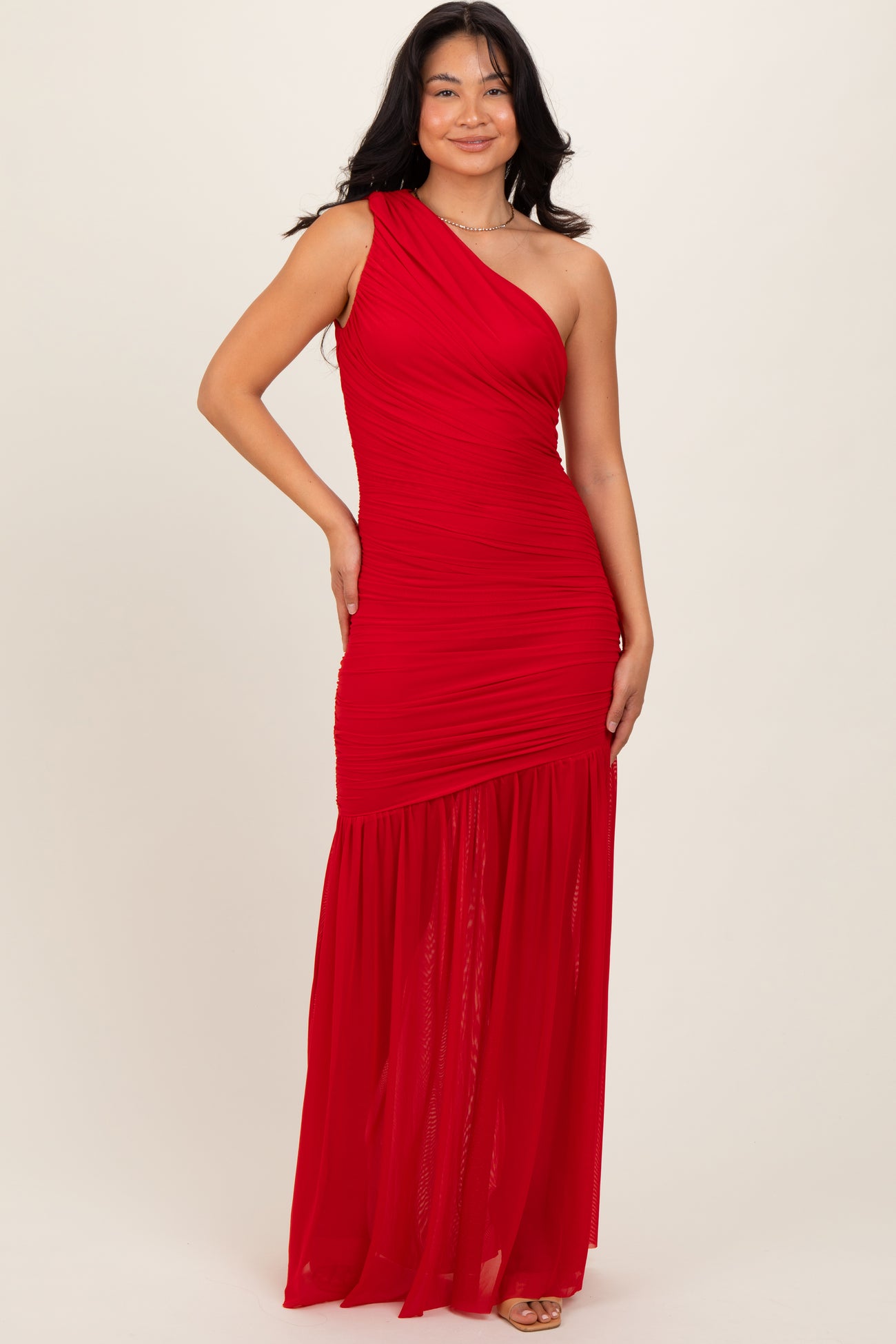 woman wearing a red one-shoulder maxi dress with ruching and a flowy skirt