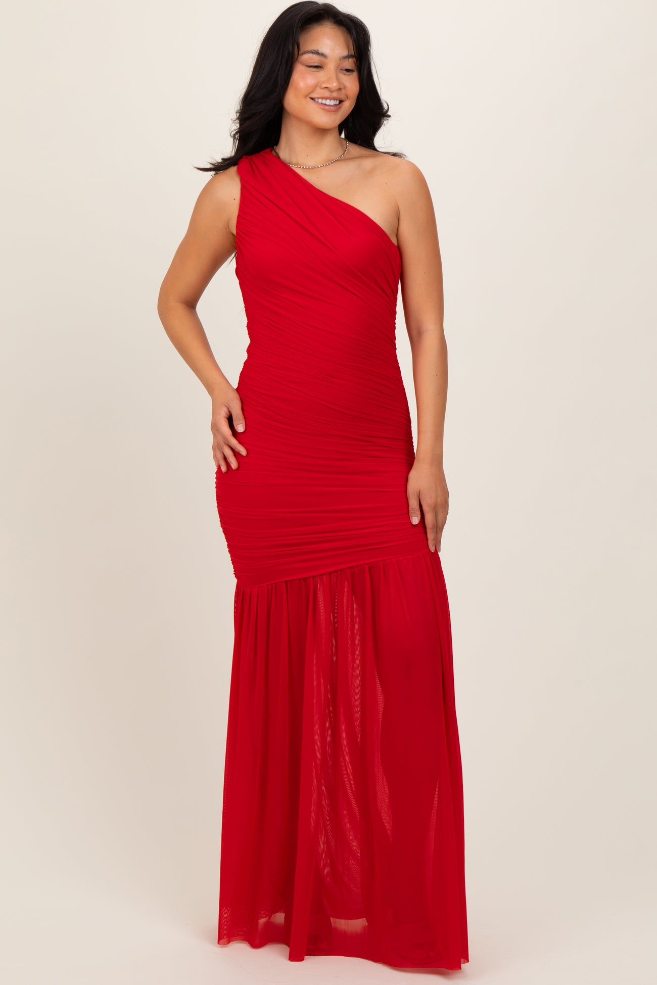 woman wearing a red one-shoulder maxi dress with ruching and a flowing skirt
