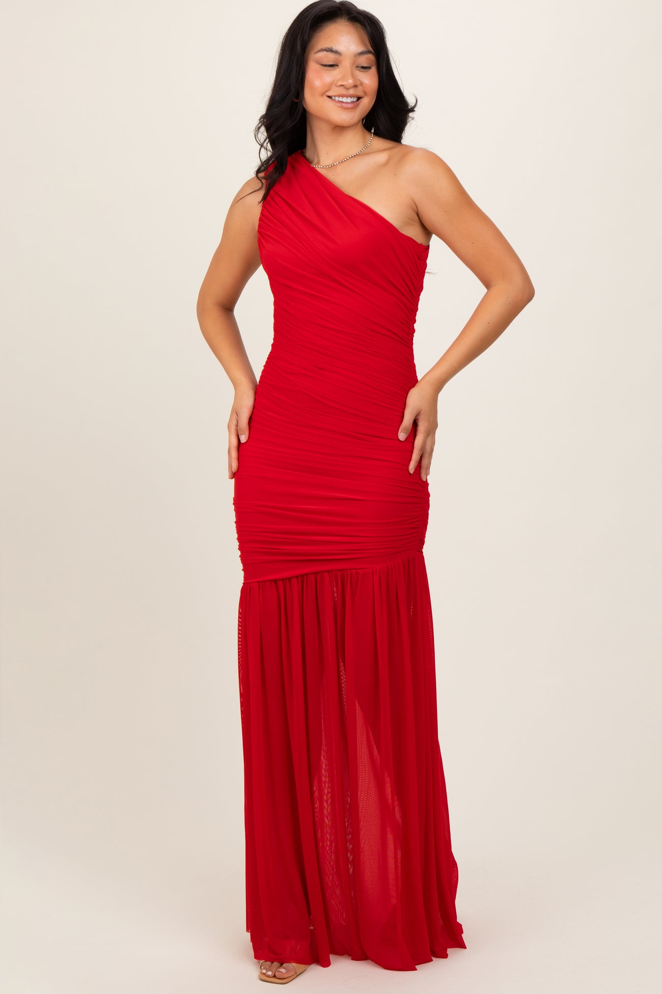 woman wearing a red one-shoulder maxi dress with ruched detailing and a flared bottom