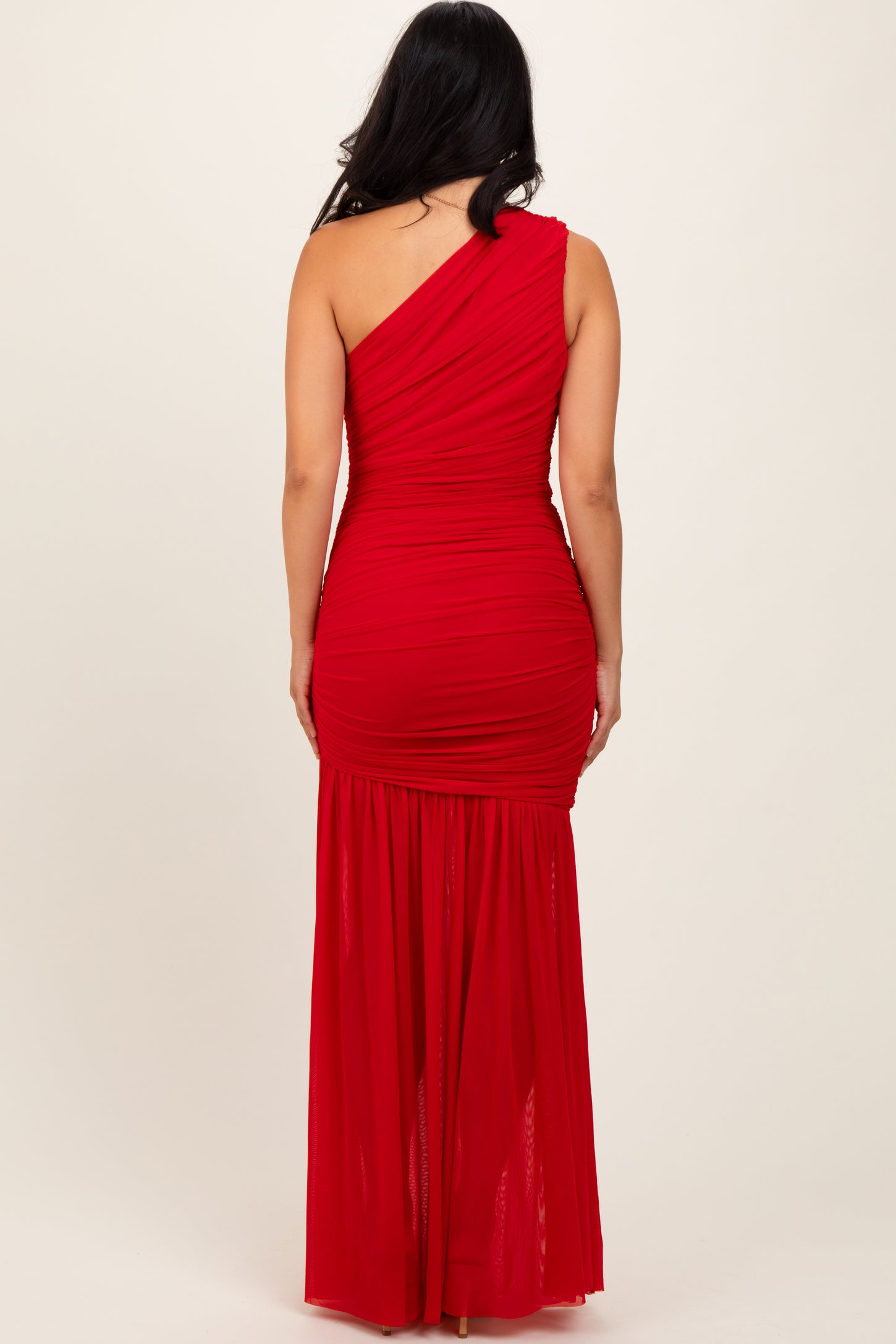 woman wearing a red one-shoulder ruched evening gown with a flowing skirt