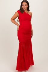 woman wearing a red one-shoulder maternity dress with ruching and a flowing skirt, showcasing her baby bump