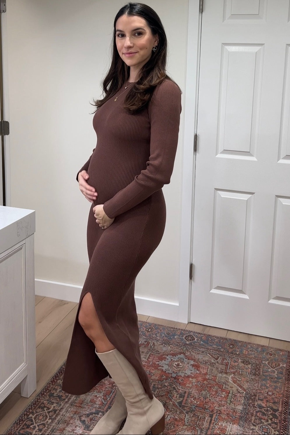 woman wearing a brown ribbed maternity dress with a side slit and holding her baby bump