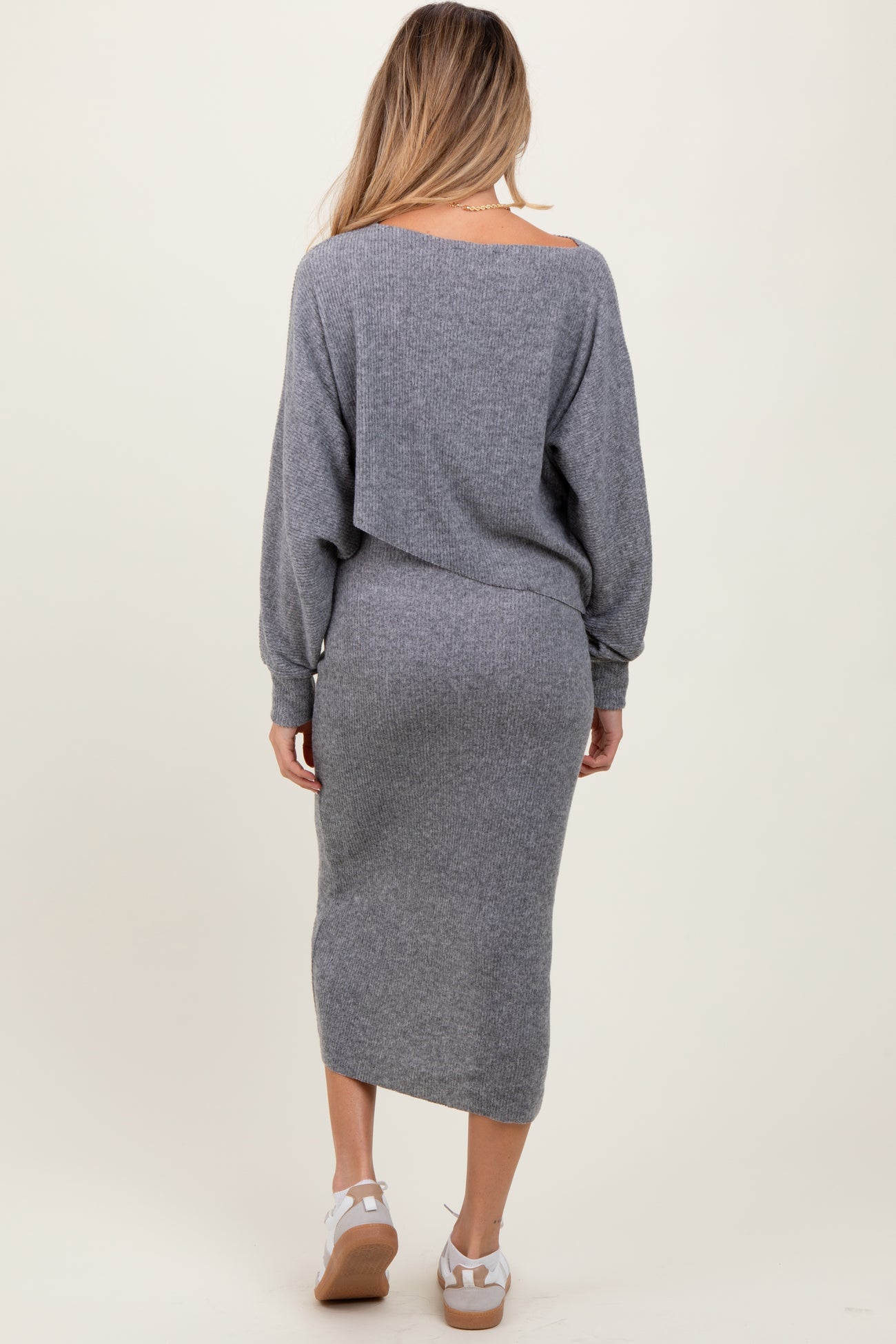 woman wearing a grey long sleeve maternity dress, showing a fitted silhouette and a mid-length hemline from the back