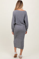 woman wearing a grey long sleeve maternity dress, showing a fitted silhouette and a mid-length hemline from the back