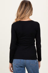 woman wearing a black long sleeve maternity top with a ruched back design and blue jeans