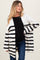 woman wearing a black and white striped maternity cardigan over a black top and showing a baby bump with dark jeans